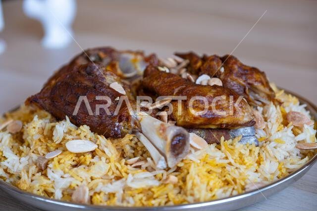 Plate of meat and rice topped with almonds on wooden table with top view