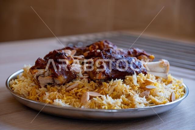 Plate of meat and rice topped with almonds on wooden table with top view