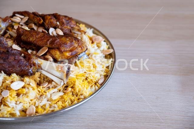 Plate of meat and rice topped with almonds on wooden table with top view