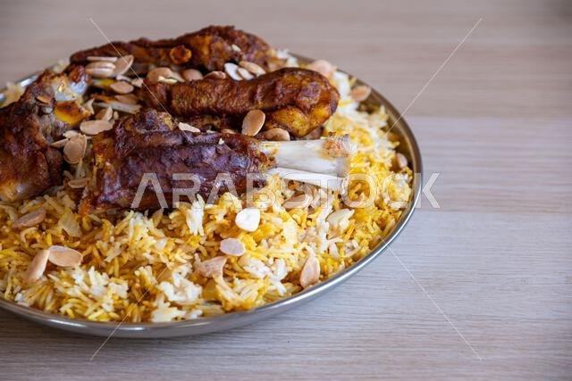Plate of meat and rice topped with almonds on wooden table with top view