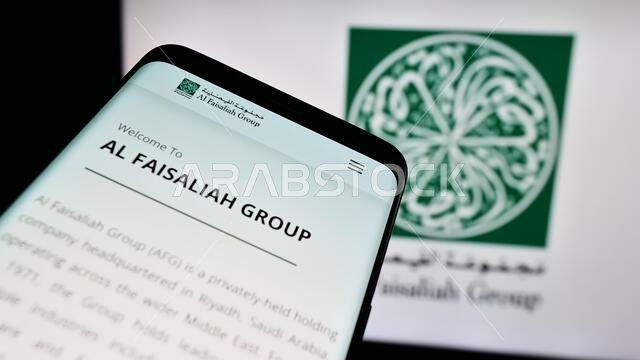 Smartphone with website of Saudi Arabian company Al Faisaliah Group in front of business logo. Focus on top-left of phone display. Smartphone with website of Saudi Arabian company Al Faisaliah Group in front of business logo. Focus on top-left of phone display.