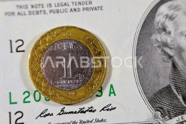 عملة معدنية من الريال السعودي لعام 2016 على خلفية ورقة نقدية من فئة دولارين أمريكيين، ورقة نقدية معدنية من الريال السعودي والدولار الأمريكي، عملات سعودية وأمريكية، 1