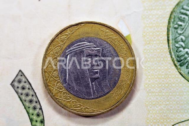 Obverse side of One Saudi Arabia riyal coin year 2016 on 1 Saudi riyal paper banknote background, one metal and banknote Saudi riyals together, 1 Saud Obverse side of One Saudi Arabia riyal coin year 2016 on 1 Saudi riyal paper banknote background, one metal and banknote Saudi riyals together, 1 Saud