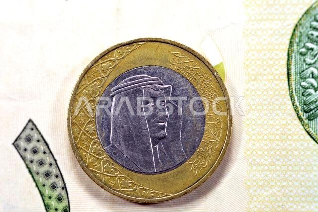الوجه الأمامي لعملة الريال السعودي لعام 2016 على خلفية ورقة نقدية من فئة الريال السعودي، ريال سعودي واحد وريال سعودي واحد معًا، 1 سعودي