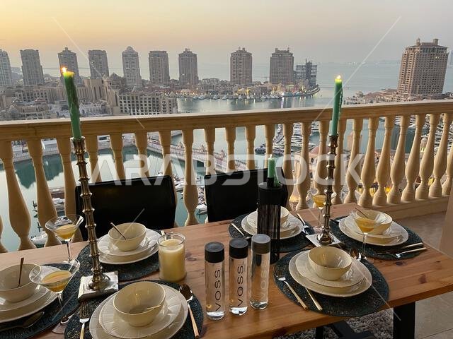 طاولة عشاء على سطح مبنى اللؤلؤة قطر مع إطلالة على غروب الشمس. إطلالة على ميناء اللؤلؤة قطر من الشرفة.