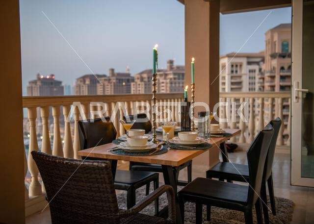 طاولة عشاء على سطح مبنى اللؤلؤة قطر مع إطلالة على غروب الشمس. إطلالة على ميناء اللؤلؤة قطر من الشرفة.