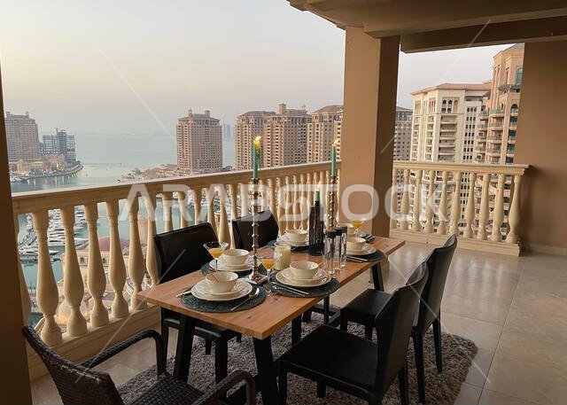طاولة عشاء على سطح مبنى اللؤلؤة قطر مع إطلالة على غروب الشمس. إطلالة على ميناء اللؤلؤة قطر من الشرفة. طاولة عشاء على سطح مبنى اللؤلؤة قطر مع إطلالة على غروب الشمس. إطلالة على ميناء اللؤلؤة قطر من الشرفة.
