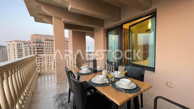 طاولة عشاء على سطح مبنى اللؤلؤة قطر مع إطلالة على غروب الشمس. إطلالة على ميناء اللؤلؤة قطر من الشرفة.