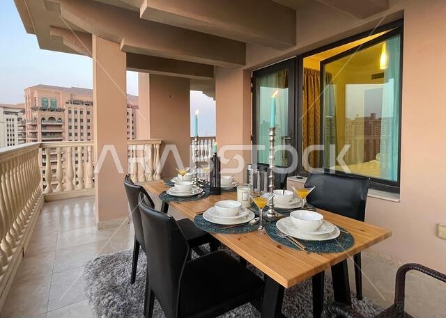 طاولة عشاء على سطح مبنى اللؤلؤة قطر مع إطلالة على غروب الشمس. إطلالة على ميناء اللؤلؤة قطر من الشرفة.