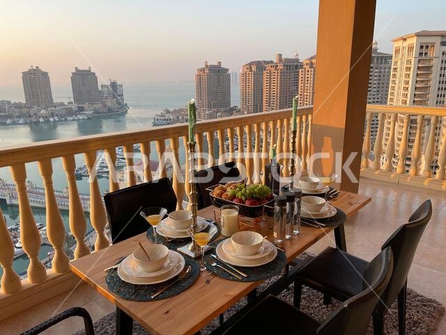 طاولة عشاء على سطح مبنى اللؤلؤة قطر مع إطلالة على غروب الشمس. إطلالة على ميناء اللؤلؤة قطر من الشرفة.