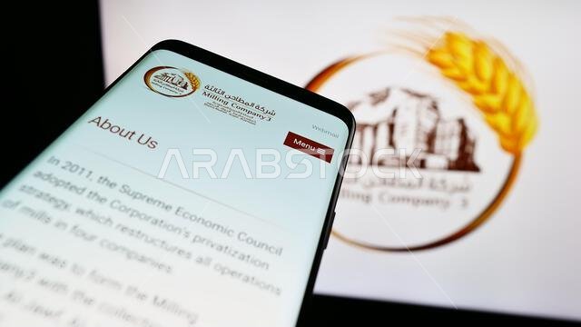 Mobile phone with website of Saudi Arabian business Milling Company 3 (MC3) on screen in front of logo. Focus on top-left of phone display.