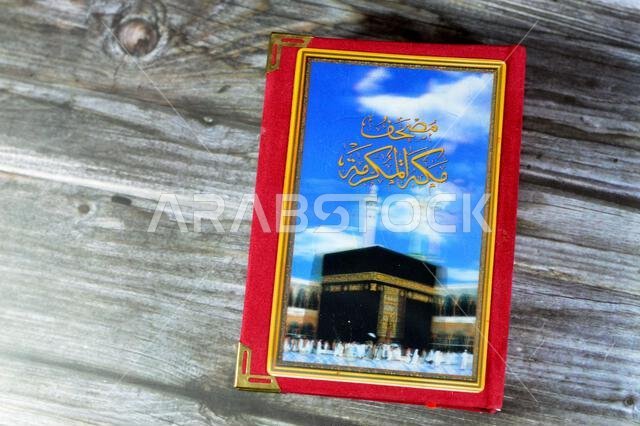 Makkah al-Mukarramah or Mecca the honored Quran  textbook, with a blurry glowing picture of Al Masjid Al Haram with Kaaba and minarets, Central book o