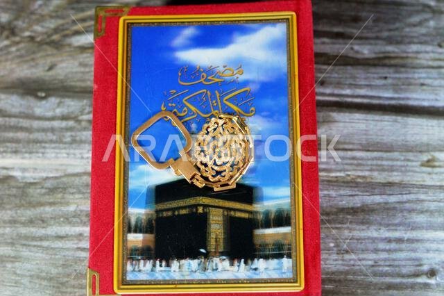 Makkah al-Mukarramah or Mecca the honored Quran, with blurry glowing picture of Kaaba, with a Golden keyring medal, Translation of Arabic (God is the Makkah al-Mukarramah or Mecca the honored Quran, with blurry glowing picture of Kaaba, with a Golden keyring medal, Translation of Arabic (God is the