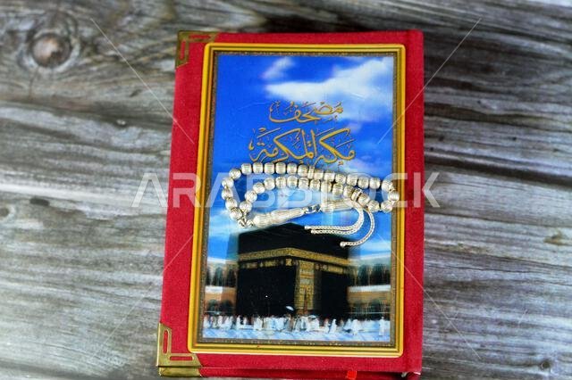 Makkah al-Mukarramah or Mecca the honored Quran textbook, with a blurry glowing picture of Al Masjid Al Haram, with a silver Islamic rosary 33 beads Makkah al-Mukarramah or Mecca the honored Quran textbook, with a blurry glowing picture of Al Masjid Al Haram, with a silver Islamic rosary 33 beads