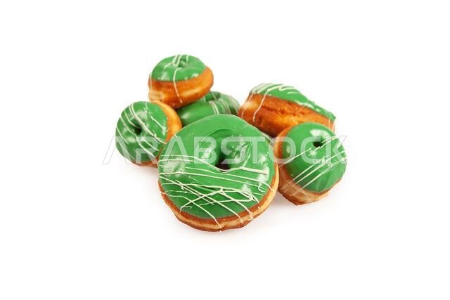 Green coloured large and mini doughnuts with white icing for special occasions.