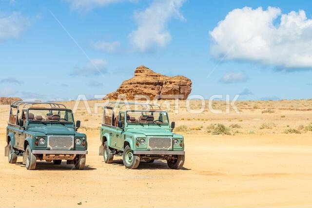 Off-road cars and desert cliffs formations landscape at Hegra, Al Ula, Saudi Arabia