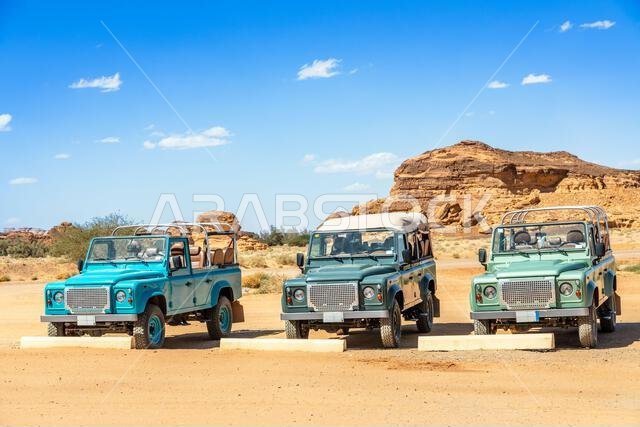 Off-road cars and desert cliffs formations landscape at Hegra, Al Ula, Saudi Arabia Off-road cars and desert cliffs formations landscape at Hegra, Al Ula, Saudi Arabia