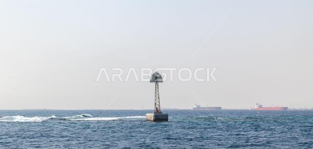Beacon tower mounted on the border of a fairway, framed structure with triangle top mark stands in water of Persian Gulf, Saudi Arabia