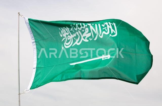 علم المملكة العربية السعودية يرفرف على سارية العلم في سماء ملبدة بالغيوم