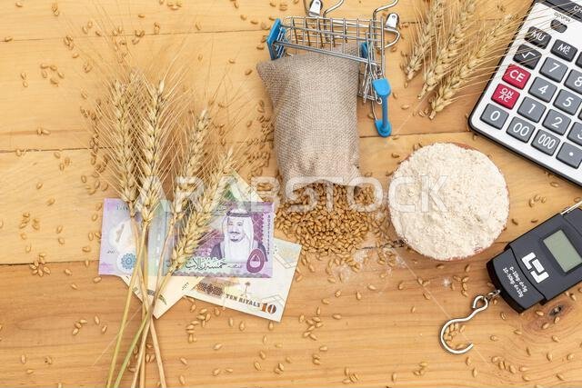 wheat spike on Saudi riyal with wheat grains and flour a wooden background. Wheat price concept
