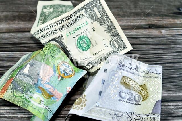 عملات سعودية وكويتية مجعدة ومتكسرة، 20 ريالاً سعودياً، دولار أمريكي واحد، تضخم العملة وفقدان قيمتها، انخفاض القيمة