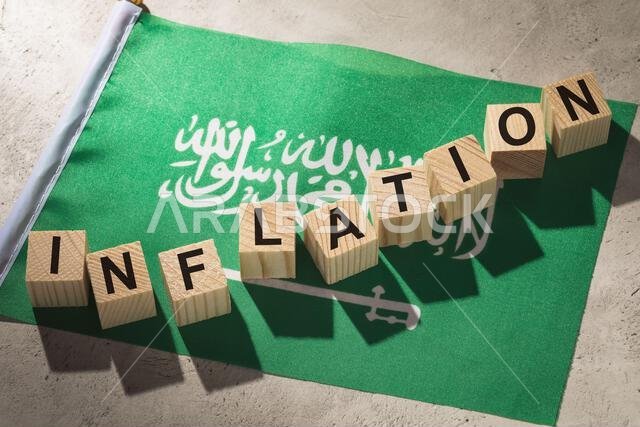 علم المملكة العربية السعودية ومكعبات خشبية عليها نصوص، وهو مفهوم يتناول موضوع التضخم في البلاد.