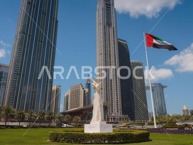 20 March 2023, Dubai, UAE: three fingers statue near UAE flag in sunny day and Burj Khalifa known as tallest skyscraper in world, United Arab Emirates. It is known for being world's tallest building. 20 March 2023, Dubai, UAE: three fingers statue near UAE flag in sunny day and Burj Khalifa known as tallest skyscraper in world, United Arab Emirates. It is known for being world's tallest building.