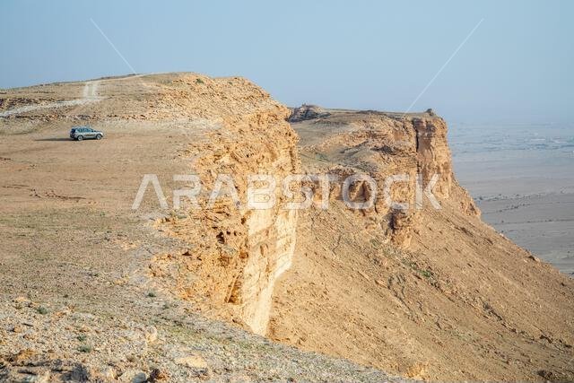 سيارة على حافة جبال جبل طويق، مع منظر صحراوي أسفلها، الرياض، المملكة العربية السعودية