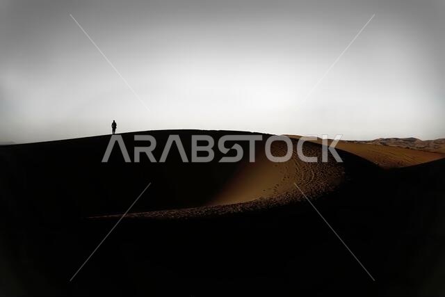 Arab man stands alone in the desert and watching the sunset.