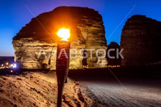 صخرة الفيل الرملية المتآكلة، المضاءة بضوء الشعلة، تقف شامخة في صحراء العلا، المملكة العربية السعودية.