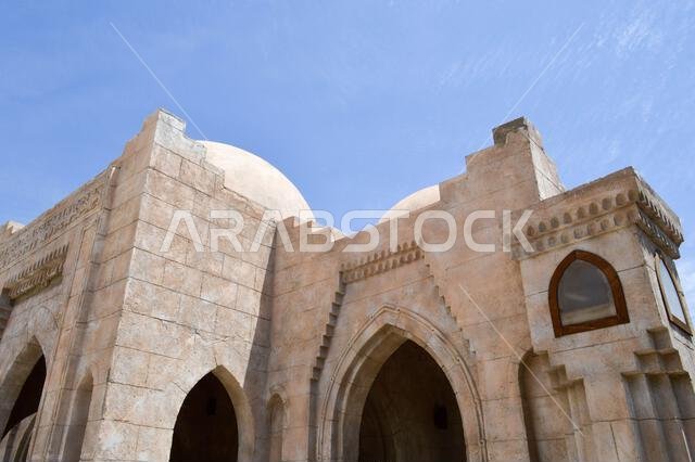 جدار ذو ملمس جميل لمسجد إسلامي عربي مبني من الطوب الأبيض، يتميز بأقواس وأبراج شاهقة وقباب وأبواب منحوتة
