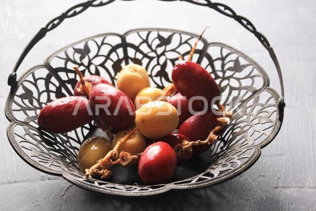 Red and Yellow Raw Dates Fruit or Kurma Muda (Ruthob) on Vintage Basket Above Rustic Background.