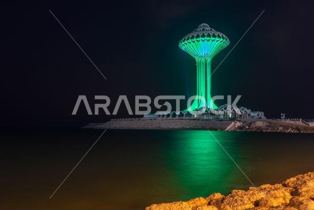 برج مياه الخبر مضاء باللون الأخضر ليلاً على شاطئ البحر، الدمام، المملكة العربية السعودية