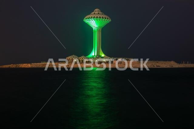 برج مياه الخبر مضاء باللون الأخضر ليلاً على شاطئ البحر، الدمام، المملكة العربية السعودية