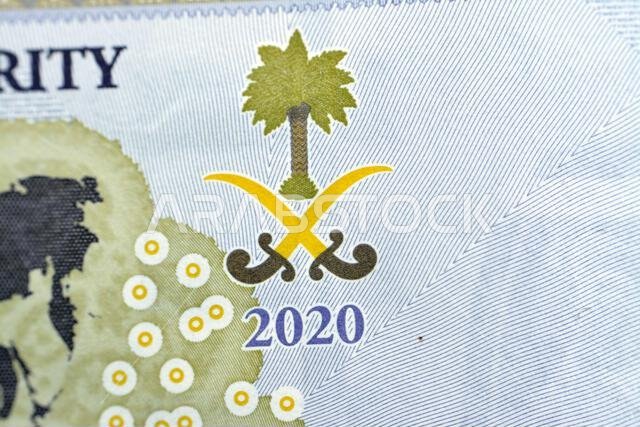 شعار المملكة العربية السعودية على الوجه الخلفي لفئة 20 ريالًا سعوديًا، وهي عملة تذكارية تحمل خريطة العالم.