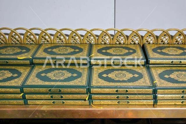 Stacks of green and golden Quran or Quraan books at shelf, closeup detail