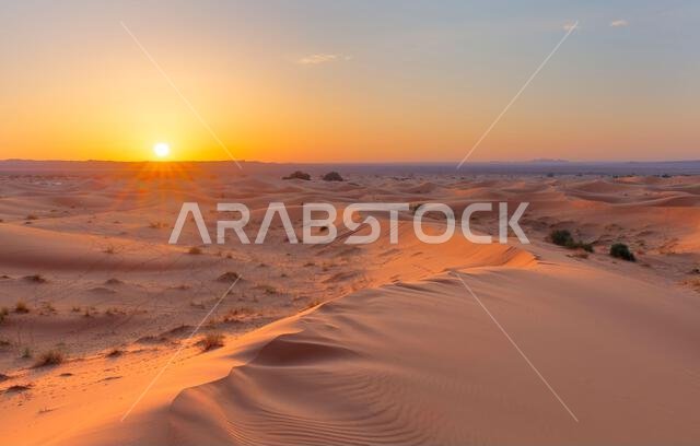 Sunset over the sand dunes in the desert. Arid landscape of the Sahara desert