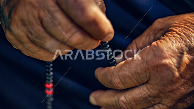 تصوير مقرب لرجل كبير في السن يستخدم السبحه لذكر الله تعالى, العباده والتقرب الى الله, إسلاميات وعبادات في يوم الجمعه