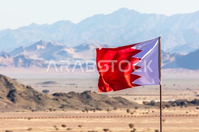 Bahrain flag waving on the wind in Saudi Arabian desertwith mountains in background, Al Ula, Saudi Arabia Bahrain flag waving on the wind in Saudi Arabian desertwith mountains in background, Al Ula, Saudi Arabia
