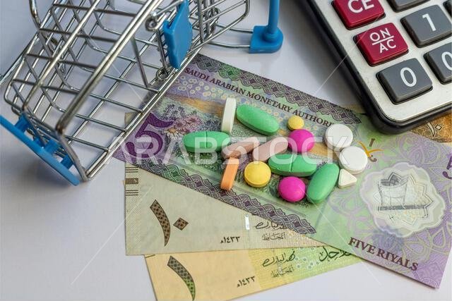 Pills and tablets in Mini shopping cart with KSA banknotes