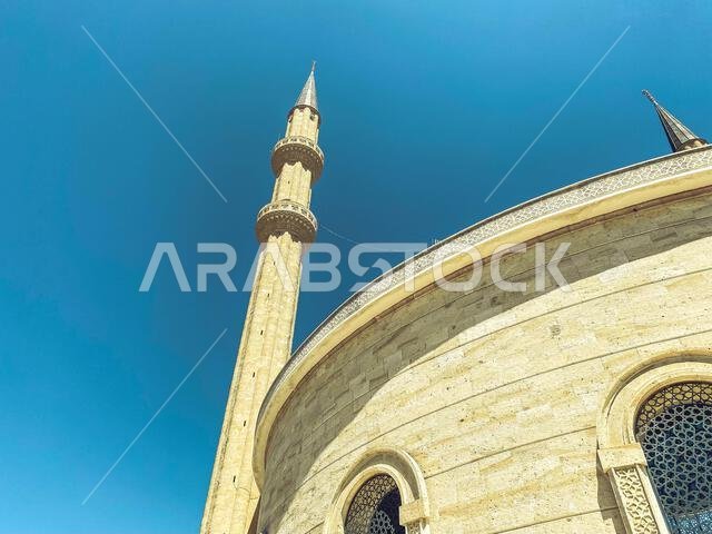 مسجدٌ على خلفية سماء زرقاء صافية. جمال بلد أجنبي، دين إسلامي. مبنى حجري ذو أبراج مدببة شاهقة.
