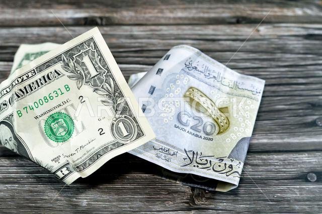 Wrinkled and crumpled Saudi Arabia money of 20 SAR twenty riyals and 1 one American dollar cash money, Money inflation and losing value, drop concept,