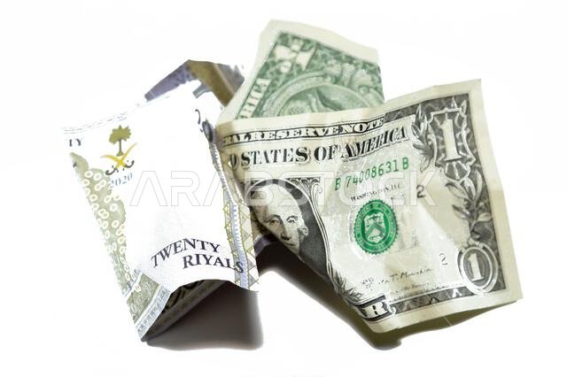 عملة سعودية مجعدة ومتكسرة من فئة 20 ريالاً سعودياً ودولار أمريكي واحد، تضخم العملة وفقدان قيمتها، مفهوم الانخفاض.