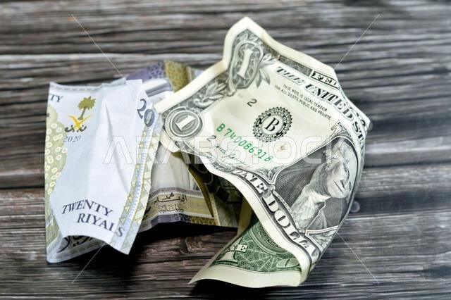 Wrinkled and crumpled Saudi Arabia money of 20 SAR twenty riyals and 1 one American dollar cash money, Money inflation and losing value, drop concept,
