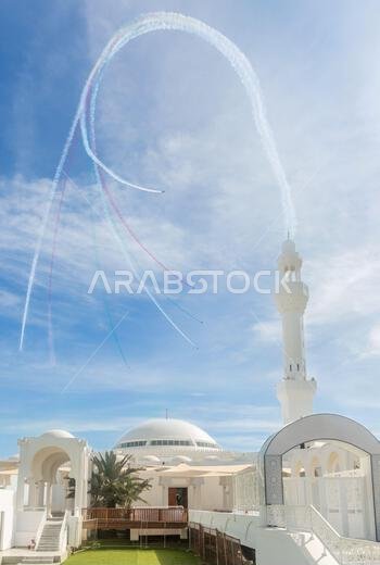 Jets stunts with smoke traces over white Alrahmah mosque, Jeddah, Saudi Arabia