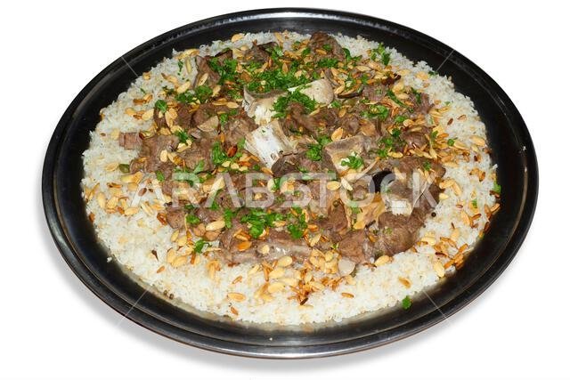 لحم الإبل مع الأرز، طبق رئيسي من المطبخ العربي التقليدي، يُقدم كغداء في مطعم مع اللوز وبذور الصنوبر.