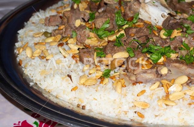 لحم الإبل مع الأرز، طبق رئيسي من المطبخ العربي التقليدي، يُقدم كغداء في مطعم مع اللوز وبذور الصنوبر.