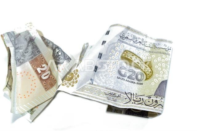 ورقة نقدية مصرية مجعدة من فئة 20 جنيهاً مصرياً، وورقة نقدية سعودية من فئة 20 ريالاً سعودياً عليها شعار قمة مجموعة العشرين، وأوراق نقدية مجعدة، وأوراق نقدية سعودية ومصرية