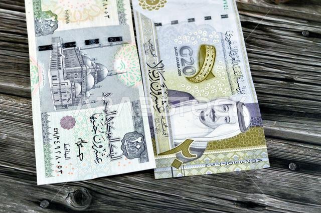 ورقة نقدية سعودية من فئة 20 ريالاً سعودياً، مع 20 جنيهاً مصرياً، وسعر صرف العملات المصرية والسعودية، وصورة لمسجد محمد علي.