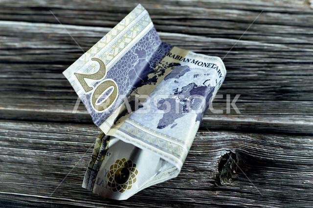 عملة سعودية مجعدة من فئة 20 ريالاً سعودياً عليها شعار قمة مجموعة العشرين، وصورة الملك سلمان، وخريطة العالم، وأوراق نقدية مجعدة، وعملة سعودية في